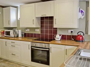 a kitchen with white cabinets and a stove top oven at Walnut Cottage in Sproughton
