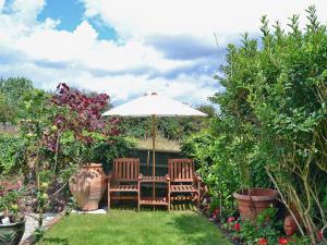 a table and two chairs under an umbrella in a garden at Walnut Cottage in Sproughton