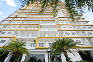 a tall white building with palm trees in front of it at MLZ Apartments Sihanoukville in Sihanoukville