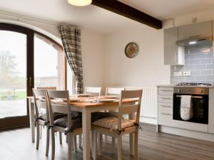a dining room with a table and chairs and a kitchen at Sunset View-e4107a in Aspatria