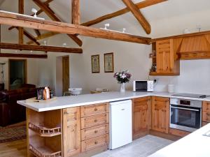 a kitchen with wooden cabinets and white appliances at Pendre Isaf in Pentre-briwnant