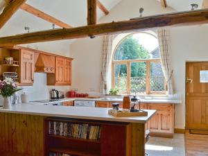 a kitchen with wooden cabinets and a large window at Pendre Isaf in Pentre-briwnant