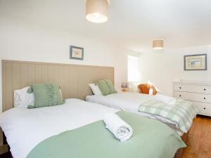 two beds in a bedroom with white and green at Cowslip Cottage in Templeton