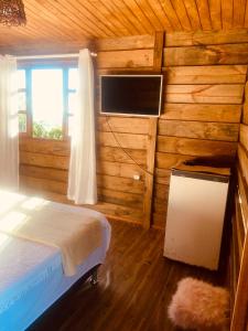 a bedroom with a bed and a tv in a log cabin at Recanto da Vila - Suíte 01 in Governador Celso Ramos