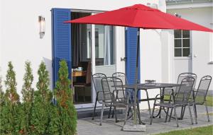 einen Tisch und Stühle mit einem roten Regenschirm auf einer Terrasse in der Unterkunft Ferienhaus 15 Altefähr in Altefähr