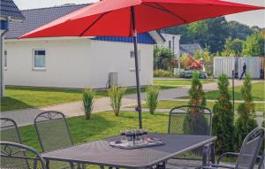 ein Tisch mit einem roten Sonnenschirm auf einer Terrasse in der Unterkunft Ferienhaus 15 Altefähr in Altefähr