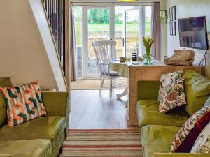 a living room with two green couches and a table at Fuggle in Ludham