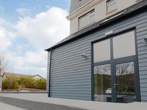 a garage with grey siding and glass windows at Rum Studio - Ukc6564 in Mallaig