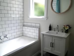 Baño blanco con bañera y lavamanos en Country Bliss Cottage en Greytown