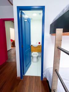 a bathroom with a toilet and a blue door at Ancestral Hostel in Bogotá