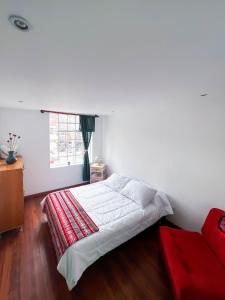 a bedroom with a white bed and a window at Ancestral Hostel in Bogotá