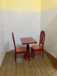Khách sạn Thanh Bình Bến Lức في Bến Lức: طاولة وكرسيين وطاولة وكراسي خشبية