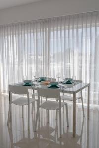 una mesa y sillas blancas con una cortina blanca en Palmer Suites en Los Prados