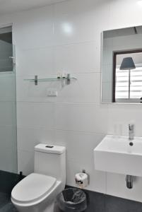 Baño blanco con aseo y lavamanos en Palmer Suites en Los Prados