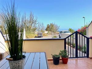 einen Balkon mit einem Holztisch und Topfpflanzen in der Unterkunft Casa La Ola - Idylle am Meer, La Lajita in Lajita