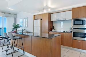 a kitchen with wooden cabinets and stainless steel appliances at Chevron Renaissance - Self Contained Apartments - Wow Stay in Gold Coast