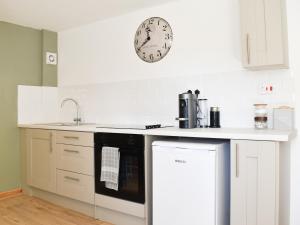 a kitchen with a stove and a clock on the wall at The Hayloft - Uk43352 in Wortley