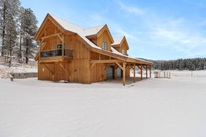 a wooden cabin with snow on the ground in the snow at Secluded Black Hills Cabin in Nemo