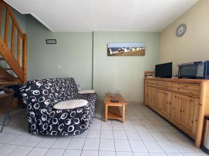 a living room with a chair and a tv at Appartement Erdeven, 3 pièces, 4 personnes - FR-1-397-68 in Erdeven