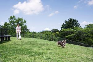 a woman walking a dog in the grass at Izu Marriott Hotel Shuzenji in Izu