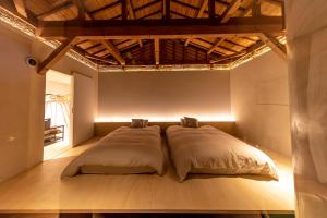 duże łóżko w pokoju z drewnianą podłogą w obiekcie オリーブの宿 澳邸 w mieście Takamatsu