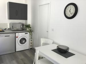 a kitchen with a washing machine and a clock on the wall at Gîte Le Petit Anzan en Indre et Loire in Noizay