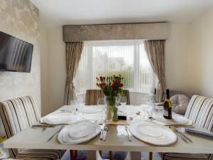 a dining room table with white plates and a window at Zoo Cottage in Chester