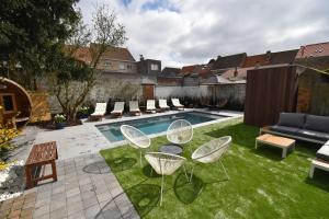 a backyard with a pool with chairs and a table at Gastenverblijf De Arend in Nieuwpoort