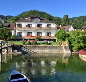 una casa y un barco en el agua junto a una casa en Hotel Sommerhaus Garni am See, en Bodman-Ludwigshafen