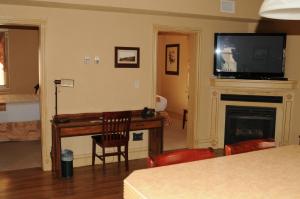 a living room with a television and a desk with a fireplace at Third Mission Heritage Suites in Peace River