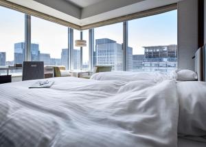 a white bed in a room with a large window at Hotel Metropolitan Tokyo Marunouchi in Tokyo
