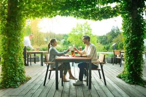 zwei Personen sitzen an einem Tisch mit Gläsern Wein in der Unterkunft Garden Village Bled in Bled