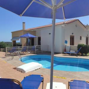 a swimming pool with blue chairs and an umbrella at Helidonia Villas in Pigi