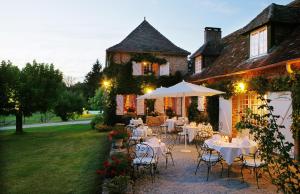 un patio con mesas y sillas frente a una casa en Hotel La Métairie - Les Collectionneurs, en Mauzac-et-Grand-Castang