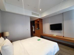 a hotel room with a bed and a flat screen tv at Hotel Tour Incheon Airport Hotel & Suites in Incheon