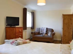 a bedroom with a bed and a chair and a television at Penmaen in Talgarth