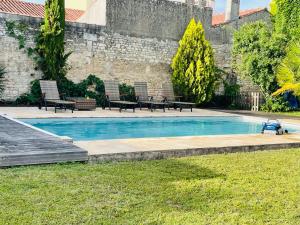 a swimming pool in a yard with benches around it at Maison de charme de 280m2 avec piscine chauffée … in Luçon