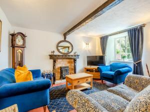 a living room with blue furniture and a fireplace at Weavers Cottage in Torquay