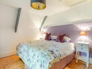 a bedroom with a bed with a purple headboard at Weavers Cottage in Torquay