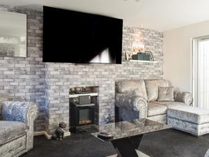 a living room with a fireplace and a tv on a brick wall at The Hawthorns in Seaham