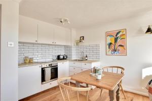 a kitchen with white cabinets and a wooden table at Nine The Boathouse in Rye