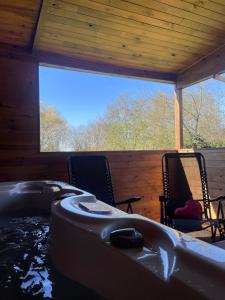 - un bain à remous dans une chambre avec 2 chaises et une baignoire dans l'établissement Au coucher du soleil, chalet avec jacuzzi et sauna, à Vieux-CondÃ©