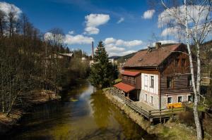 un bâtiment à côté d'une rivière avec une maison dans l'établissement Maxova Bouda, à Josefův Důl