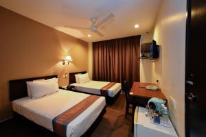 a hotel room with two beds and a desk at Good Hope Hotel Kelana Jaya in Petaling Jaya