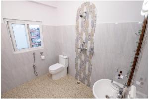 e bagno con servizi igienici, doccia e lavandino. di Hotel Tulip Pokhara Inn a Pokhara Altre 37 foto