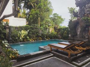 a swimming pool with two lounge chairs next to it at The Oni Bisma in Ubud