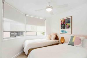 two beds in a white room with a window at Blush on Broadbeach- beachside and pet friendly in Gold Coast