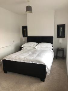 une chambre avec un grand lit avec des draps et des oreillers blancs dans l'établissement Aga Cottage, à Headwood