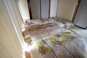 two unmade beds in a room next to a window at ヒュッテ・ボーデン in Komoro