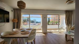 a dining room with a table and chairs and a balcony at Mediterranean apartment Rosas in Roses